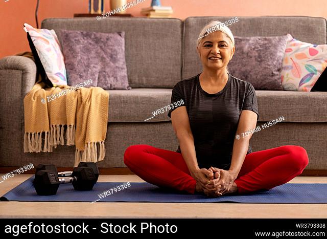 Portrait of an active old woman practising yoga at home