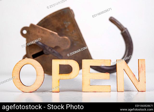 OPEN inscription made of wooden letters. Open star padlock. Light background