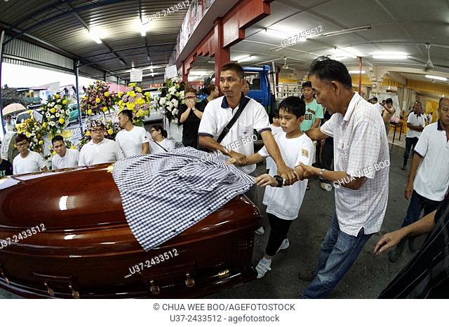 The eldest son pulling the late dad's shirt away from coffin. Sarawakian chinese funeral ceremony. Malaysia