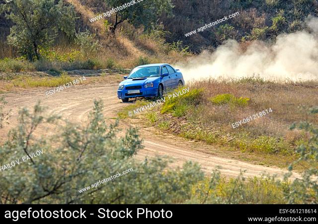 Sunny summer day. Dirt track for the rally. Car drives through a turn and makes a lot of dust