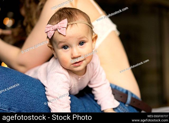 Smiling cute baby girl lying on mother's lap at home
