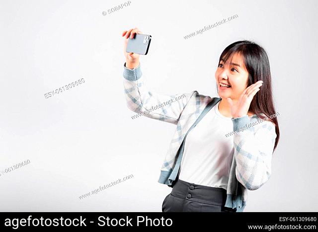 Woman excited holding smartphone to shooting selfie photo front camera studio shot isolated white background, happy young female smiling taking photography by...