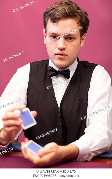 Dealer sitting at table of a casino while shuffling a deck of cards