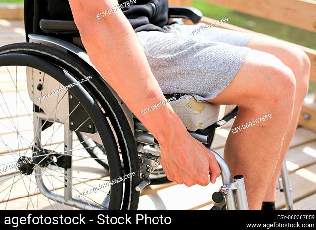 Disabled young athletic man on a wheelchair holding and turning wheels with hand engage in sports