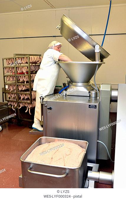 Woman cotrolling filling machine in a butchery