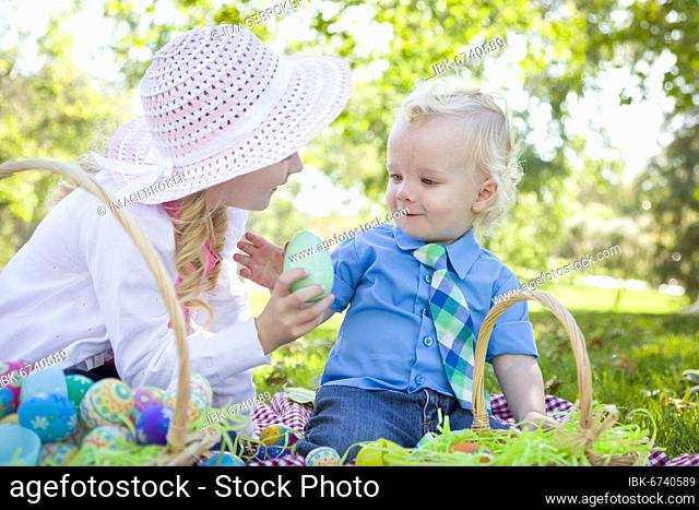 Cute young brother and sister enjoying their easter eggs outside in the park together