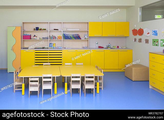 Classroom in a kindergarten school, yellow furniture and tables and blue floor
