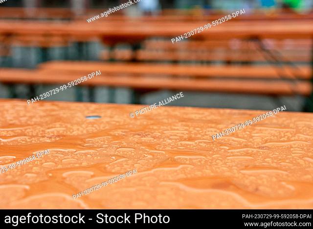 29 July 2023, Saxony-Anhalt, Wernigerode: Raindrops collect on tables and benches on the market square, which were provided for the participants of a hiking...