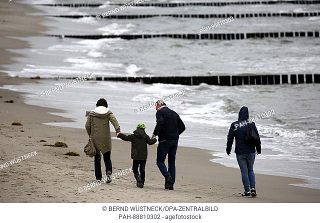 A few people walk along the Baltic Sea beach of Graal-Mueritz, Germany, 7 March 2017. Thick clouds creat a grey and cold weather