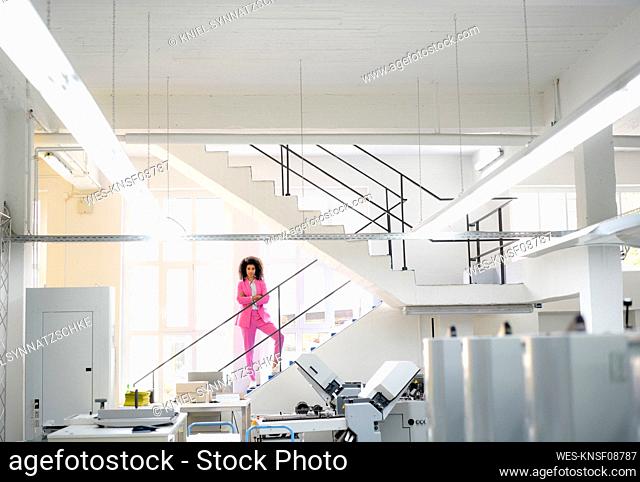 Afro businesswoman with arms crossed standing on steps in industry
