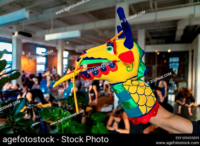 A close up and side profile view of a hand puppet on the arm of a person, a colorful and fun dragons head used to motivate people during grueling gym workout
