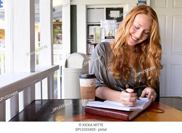 A woman writing notes in a coffee shop;Kauai hawaii united states of america