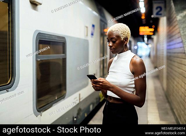 Young woman using mobile phone while standing at subway station