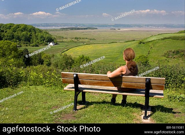 Woman sitting on bench overlooking the coast, Llanmadoc, Llanridian Sands, Burry Port, Gower Peninsula, Glamorgan, Wales, United Kingdom, Europe