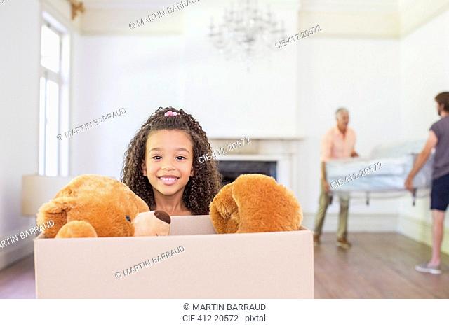 Young girl carrying box with teddy bear inside