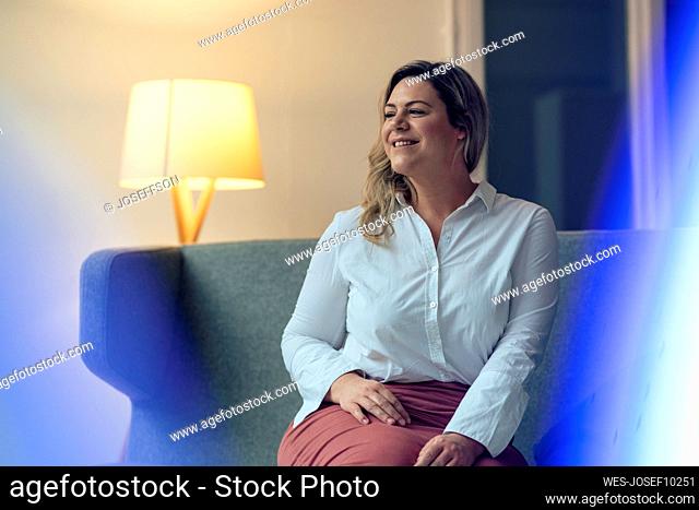 Contemplative businesswoman sitting on sofa at work place