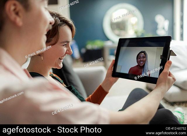 Happy young couple video chatting with friend on digital tablet screen