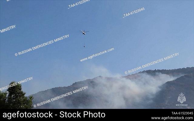 RUSSIA, GELENDZHIK - AUGUST 30, 2023: A helicopter drops water on a wildfire. Video grab. Best quality available. Russian Emergencies Ministry/TAS