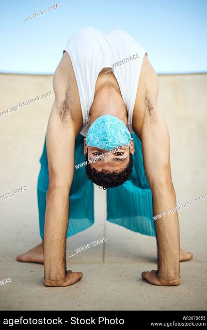 Young man wearing mask practicing wheel pose on sports ramp