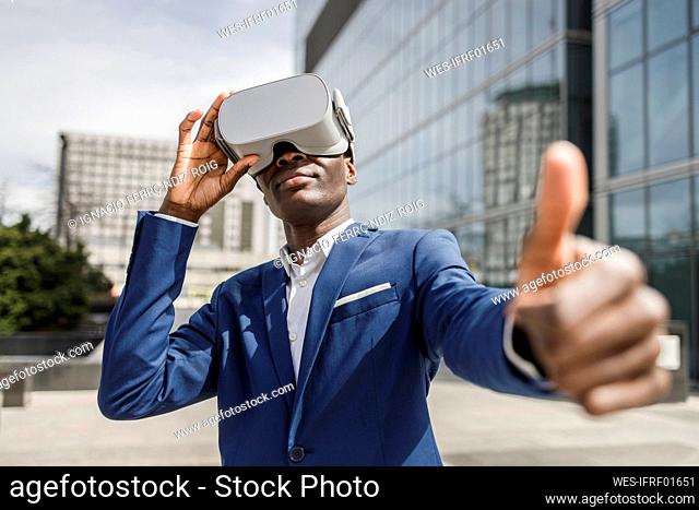 Businessman wearing virtual reality simulator showing thumbs up