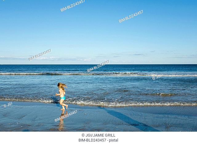 Caucasian girl running on beach