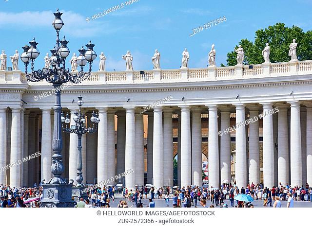 Statues of saints above a crowded Piazza San Pietro, Rome, Lazio, Italy, Europe. . In the 1650's 90 saints by Bernini were placed above the colonnades looking...