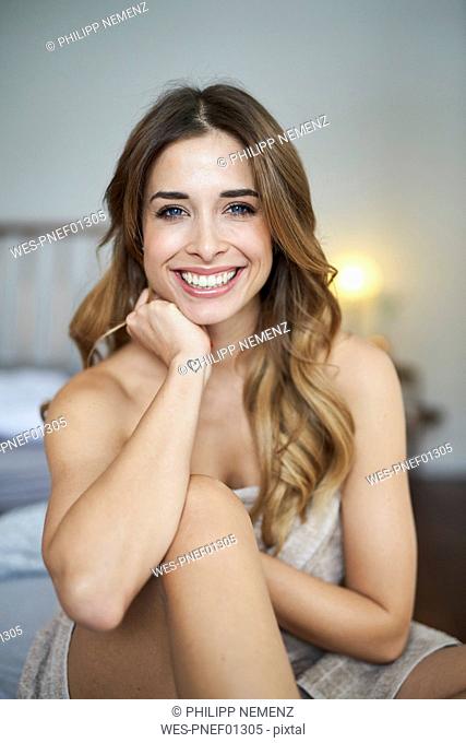 Portrait of happy young woman sitting on bed
