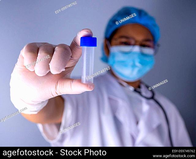 Portrait of a female doctor wearing a mask and wearing a hat Stand holding an empty vaccine or pill bottle.Medical concept and treatment