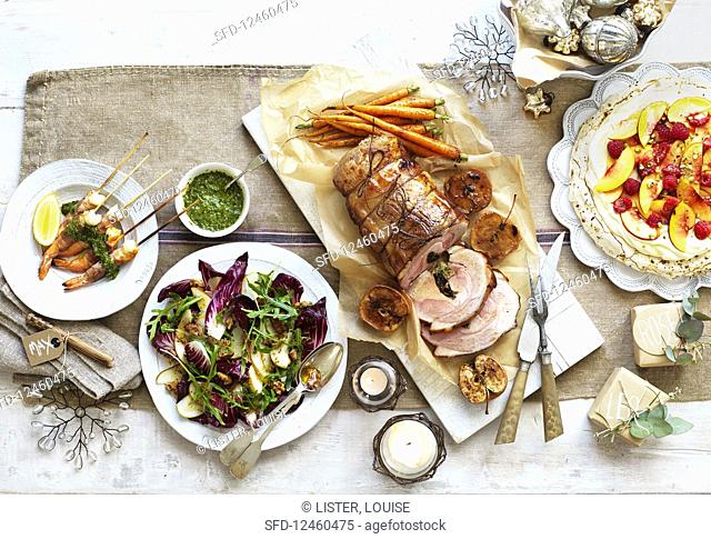 Christmas dinner with shrimps, roast pork, radicchio salad, and pavlova