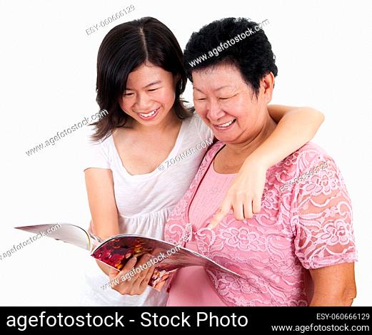 Senior mother and young daughter reading on a book, with smiling, isolated on white background
