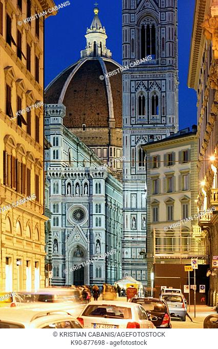 Duomo, Cathedral Santa Maria del Fiore and Campanile di Giotto seen from the street with people walking and cars parked at streetsite and at the night with...