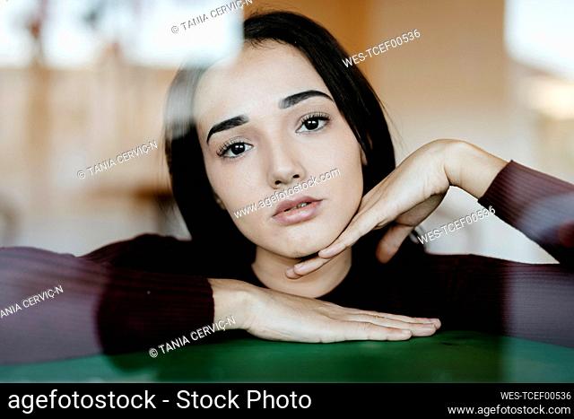 Portrait of young woman behind windowpane