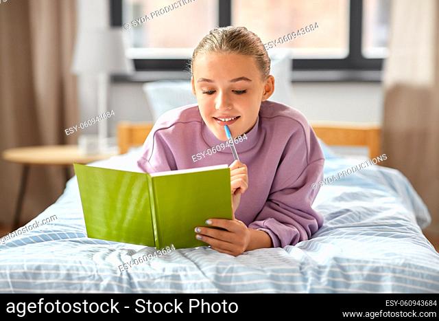 thinking girl with diary lying on bed at home