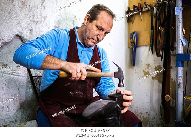 Shoemaker repairing a shoe in his workshop