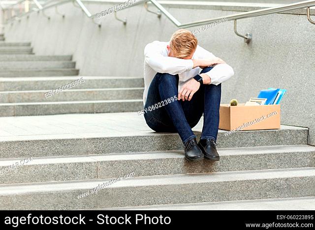 Lose job, young man lost his job, sitting on stairs holding head down, depressed, crying and don't know what to do in crisis time. feeling looser