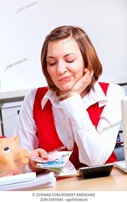 Frau schaut frustriert auf Euro-Geldscheine im Büro