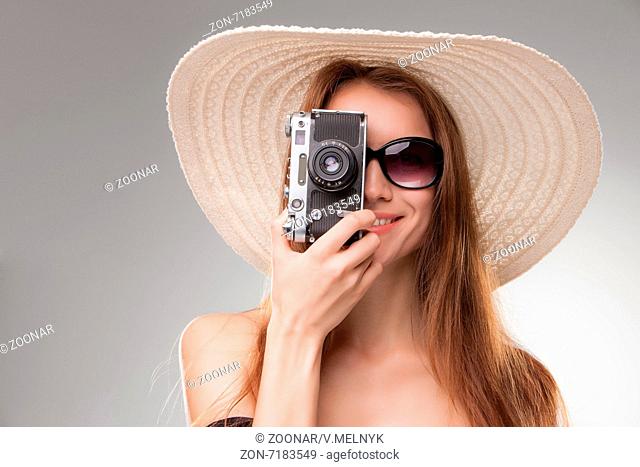 Girl in broad-brimmed hat and sunglasses with retro camera