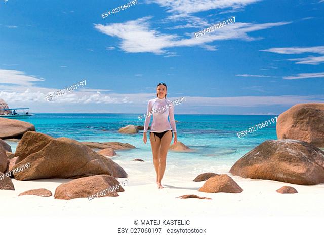 Woman wearing stylish bikini and lycra top enjoying swimming and snorkeling at amazing Anse Lazio beach on Praslin Island, Seychelles