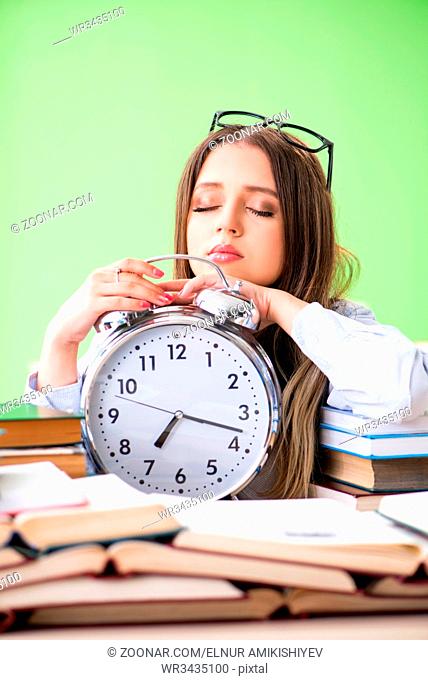 Young female student preparing for exams with many books in time management concept