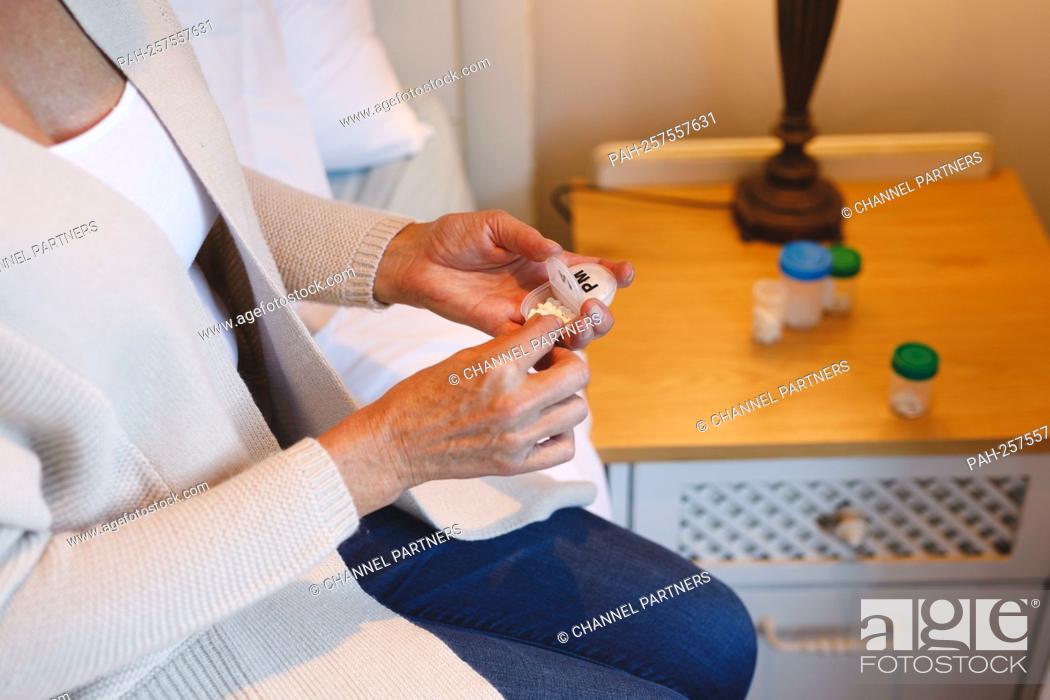 Stock Photo: Mid section of senior caucasian woman in bedroom sitting on bed, holding pills. retirement lifestyle, illness and the aging process || Model approval available.