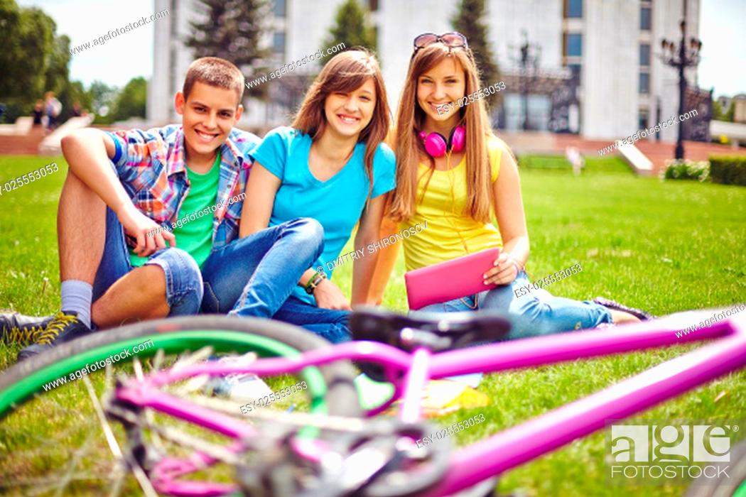 Stock Photo: Cheerful teenage friends relaxing on green lawn in summer.