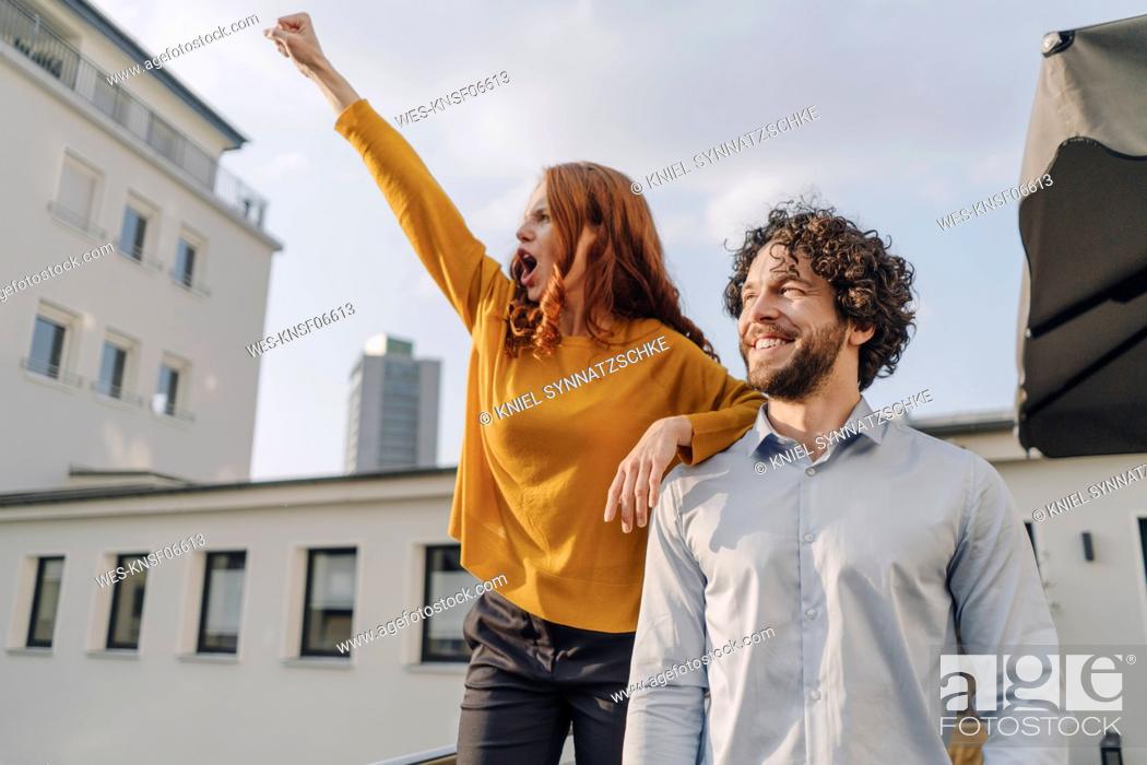 Stock Photo: Woman with colleague on roof terrace clenching fist.